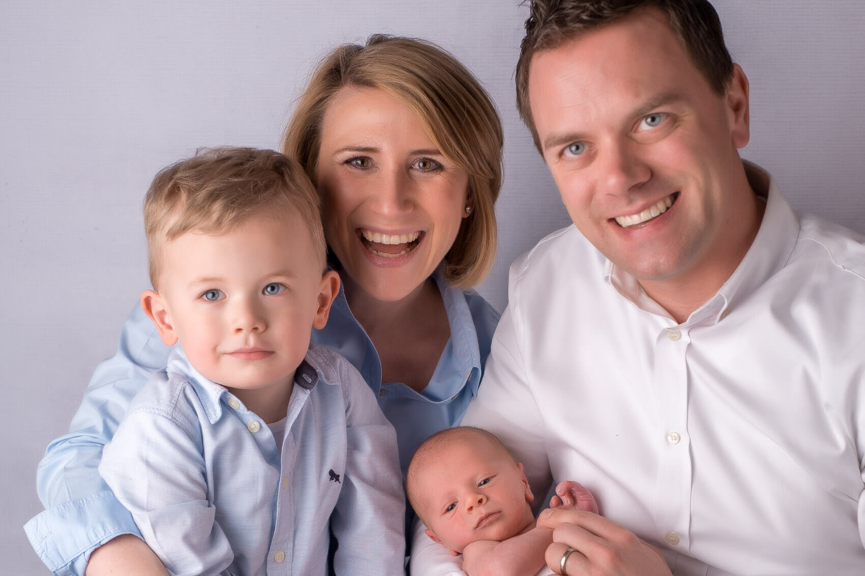 Lächelnde Eltern halten ihr Baby bei einem Familienfotoshooting