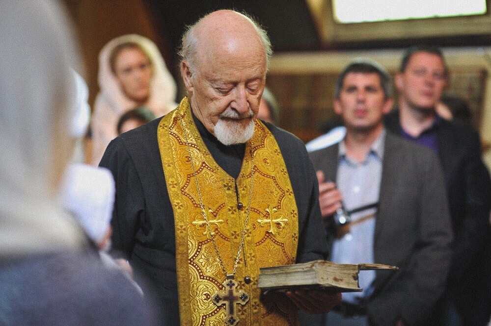 Priester liest während der Taufzeremonie aus einem alten liturgischen Buch