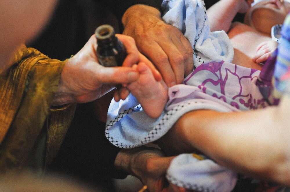 Nahaufnahme der Salbung eines Babyfußes während der kirchlichen Taufe