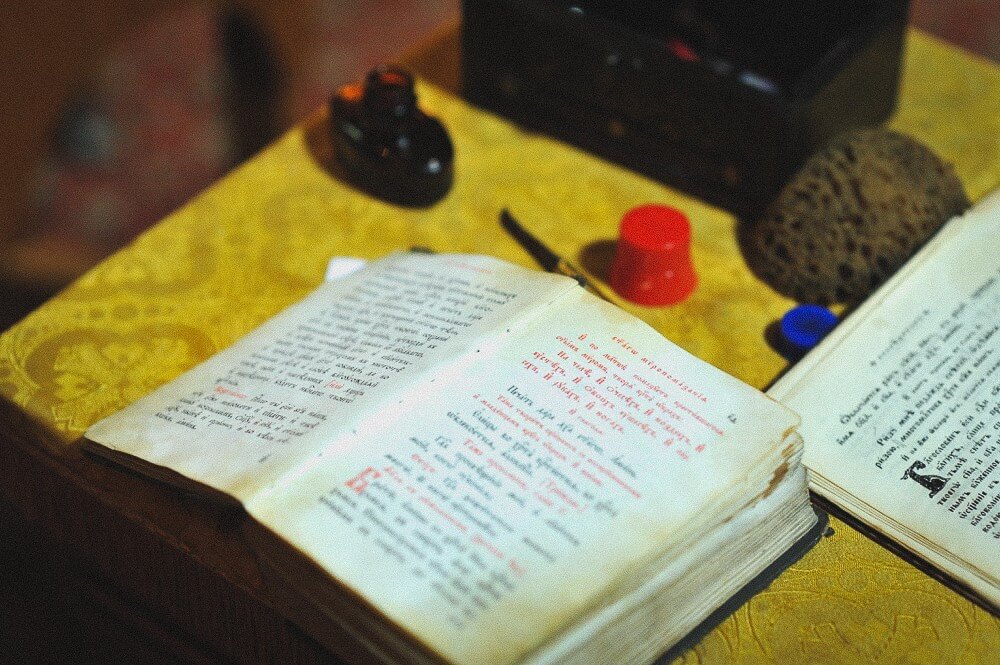Geöffnete liturgische Bücher und Ritualgegenstände auf einem goldenen Tuch