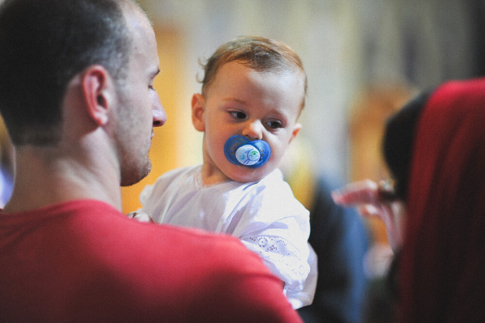 Baby im weißen Taufgewand nach der Taufe