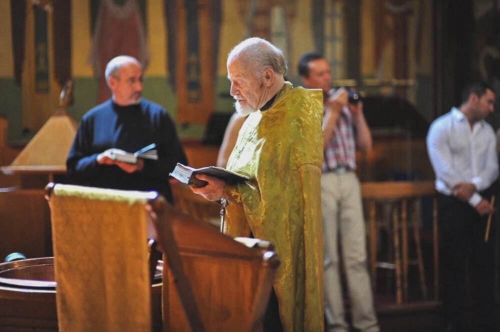 Priester liest am Taufbecken aus einem liturgischen Buch