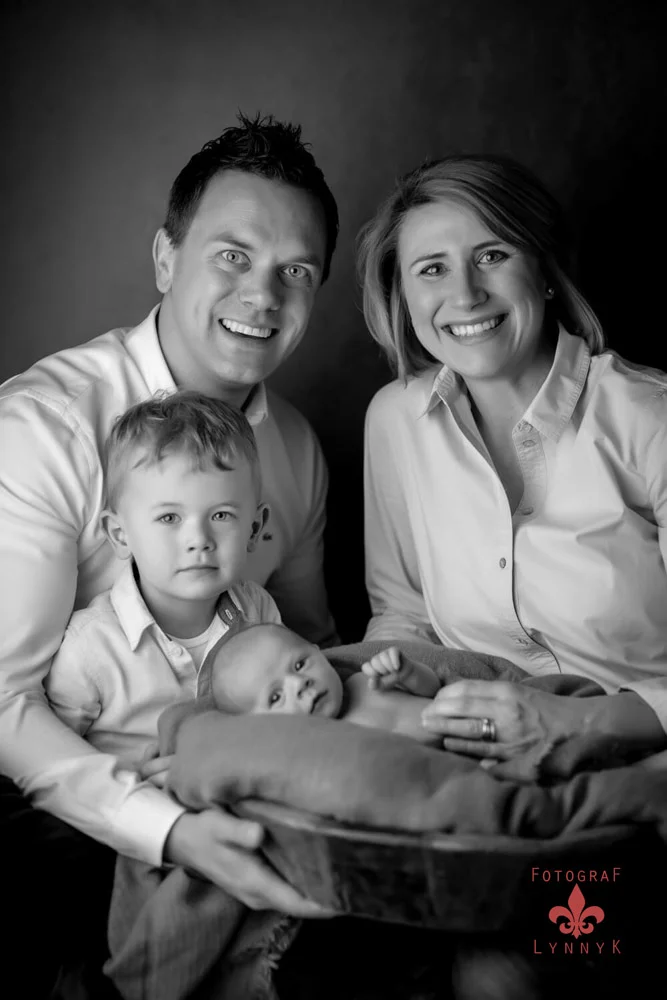 Familie lacht mit Baby in Schwarz-Weiß – ungestellter, emotionaler Moment.