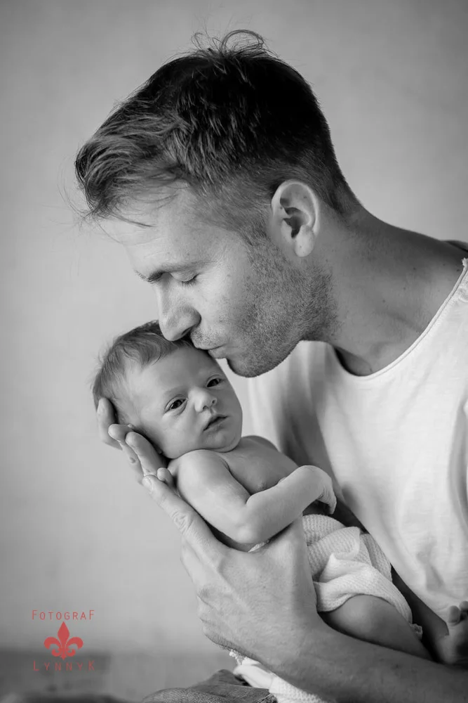 Eltern küssen Baby auf Stirn – zärtlicher Augenblick der Liebe.