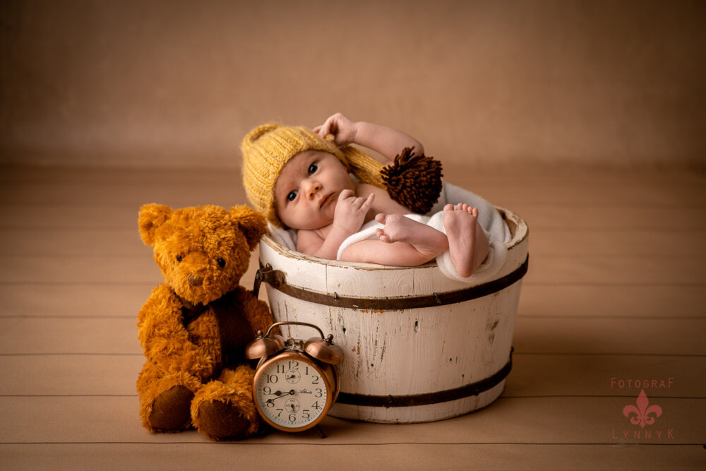 Neugeborenes mit Teddy und Uhr in Holztopf – babyfotograf frankfurt setzt Accessoires gekonnt ein